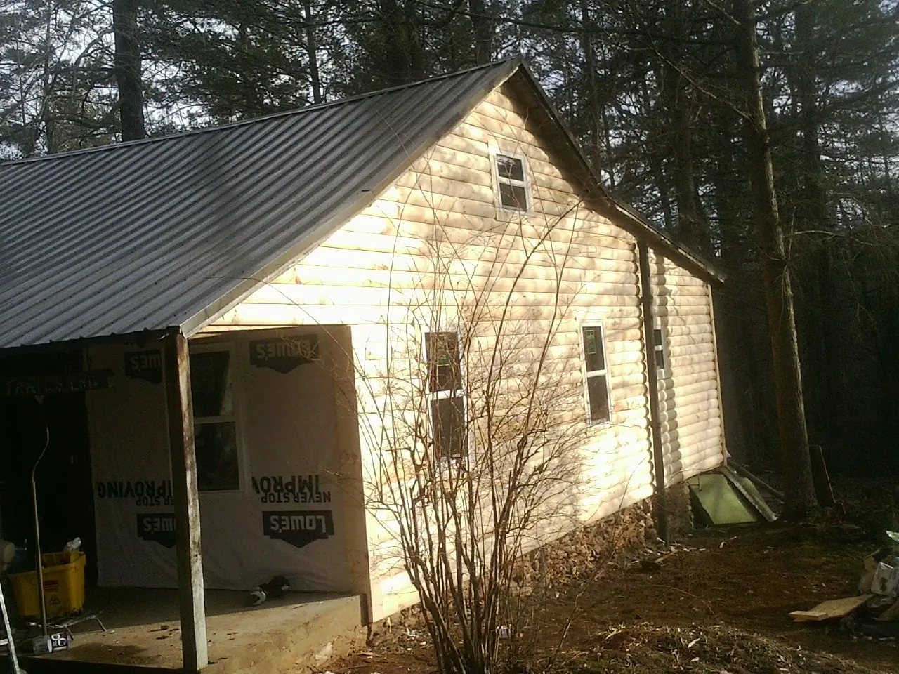 Log siding gable end under a dark metal roof edge in Kenmore
