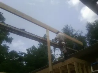 Carpenter setting a ridge beam over a new addition frame — Ice Dam Removal by Roofing Brothers in Kenmore