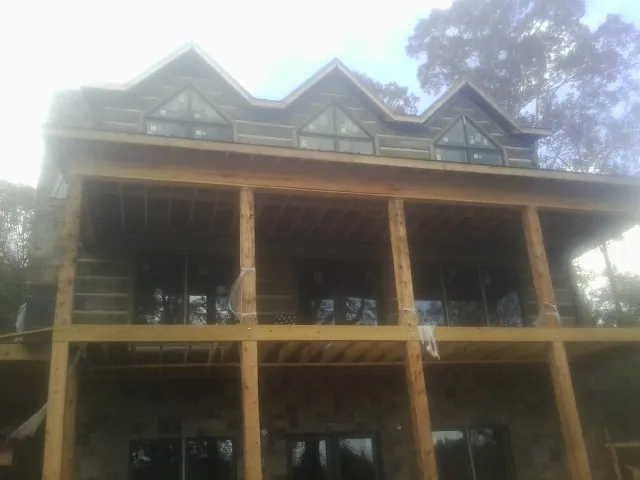 Dormers and porch framing on a large log home under construction — Roof Coating work by our crew in Kenmore