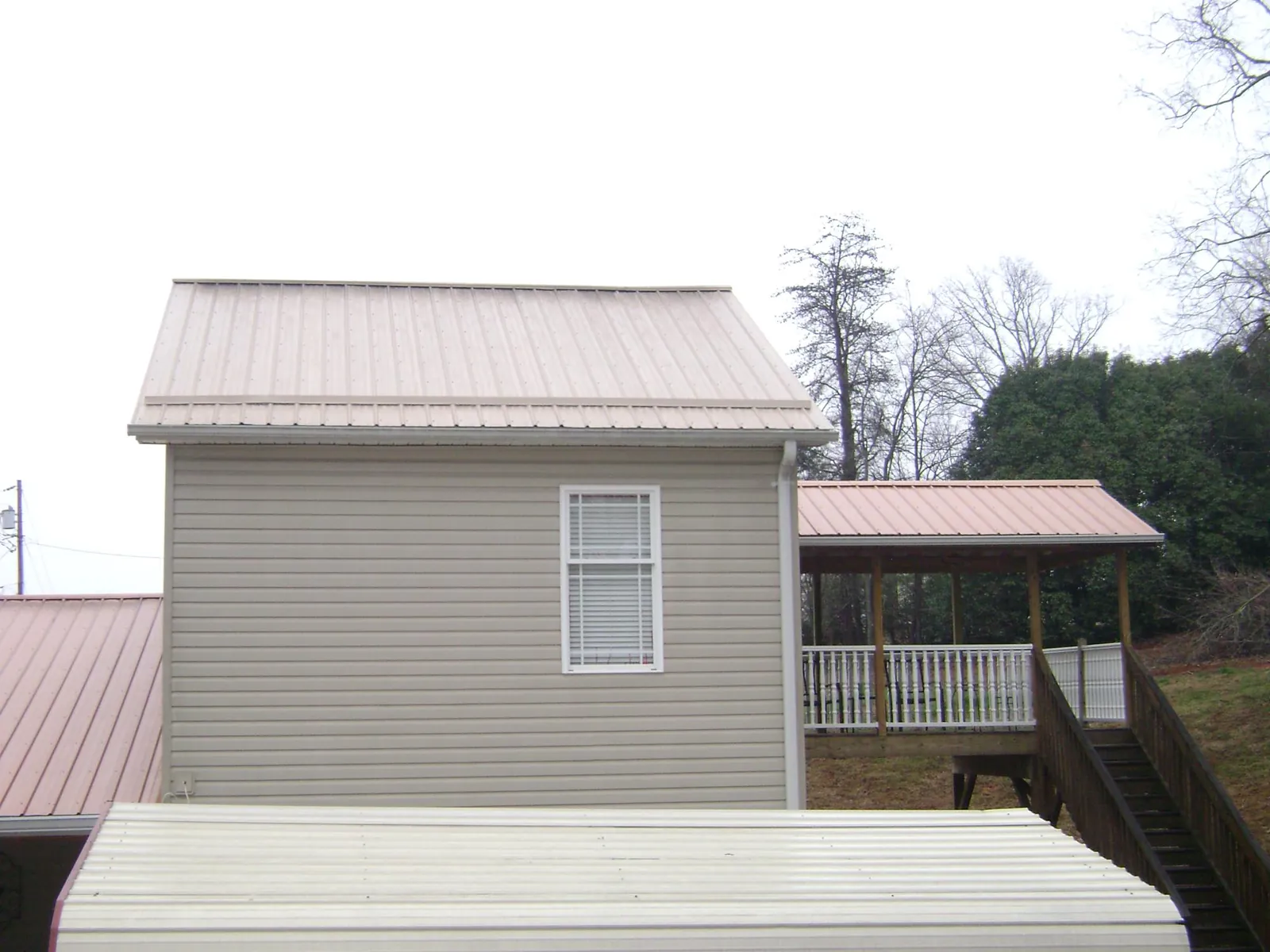 Tan metal roofs on a two story addition and attached porch, from a Roof Replacement job in Kenmore