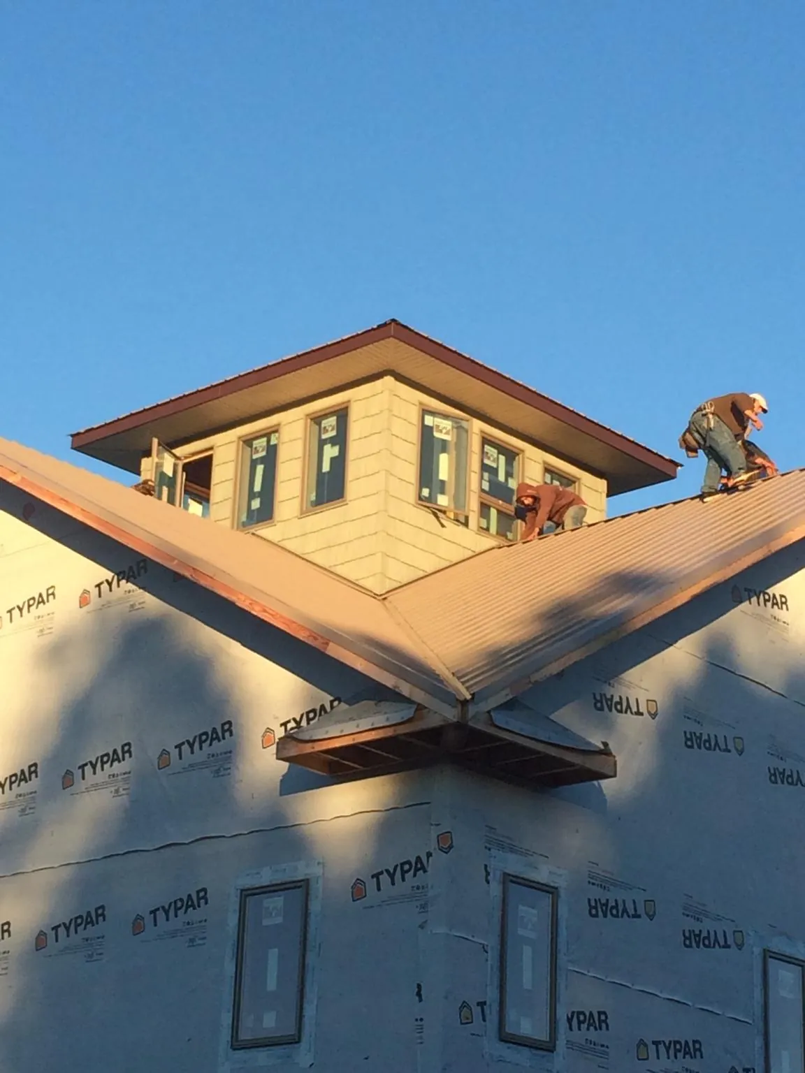Roofers working around a rooftop cupola on a new metal roof at sunset — Roof Waterproofing in Kenmore by Roofing Brothers
